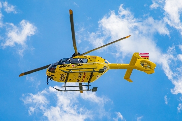 Rettungshubschrauber des ADAC und ÖAMTC fliegt durch blauen Himmel