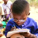 Junges Mädchen aus Malawi liest das erste mal mit Brille 