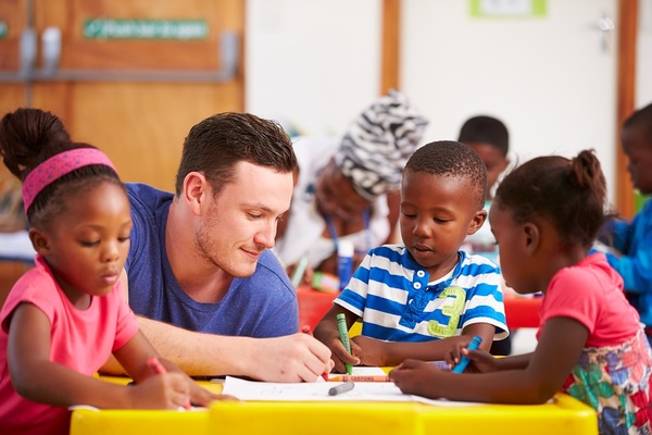 Lehrer mit Kindern am Tisch FSJ