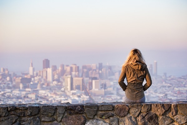 Blonde Frau auf Mauer vor Stadt